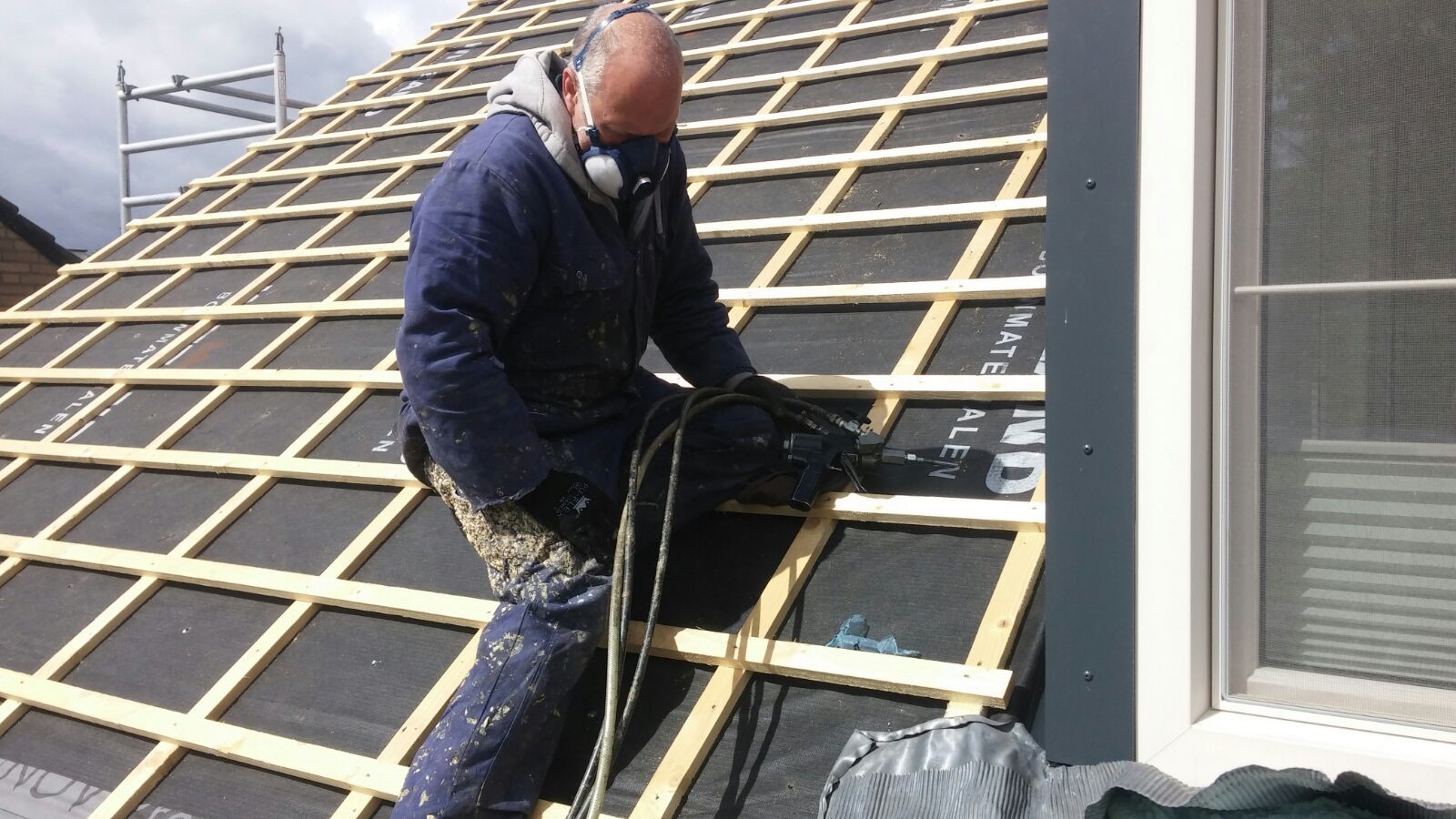 Man op het dak spuit isolatieschuim in compartimenten
