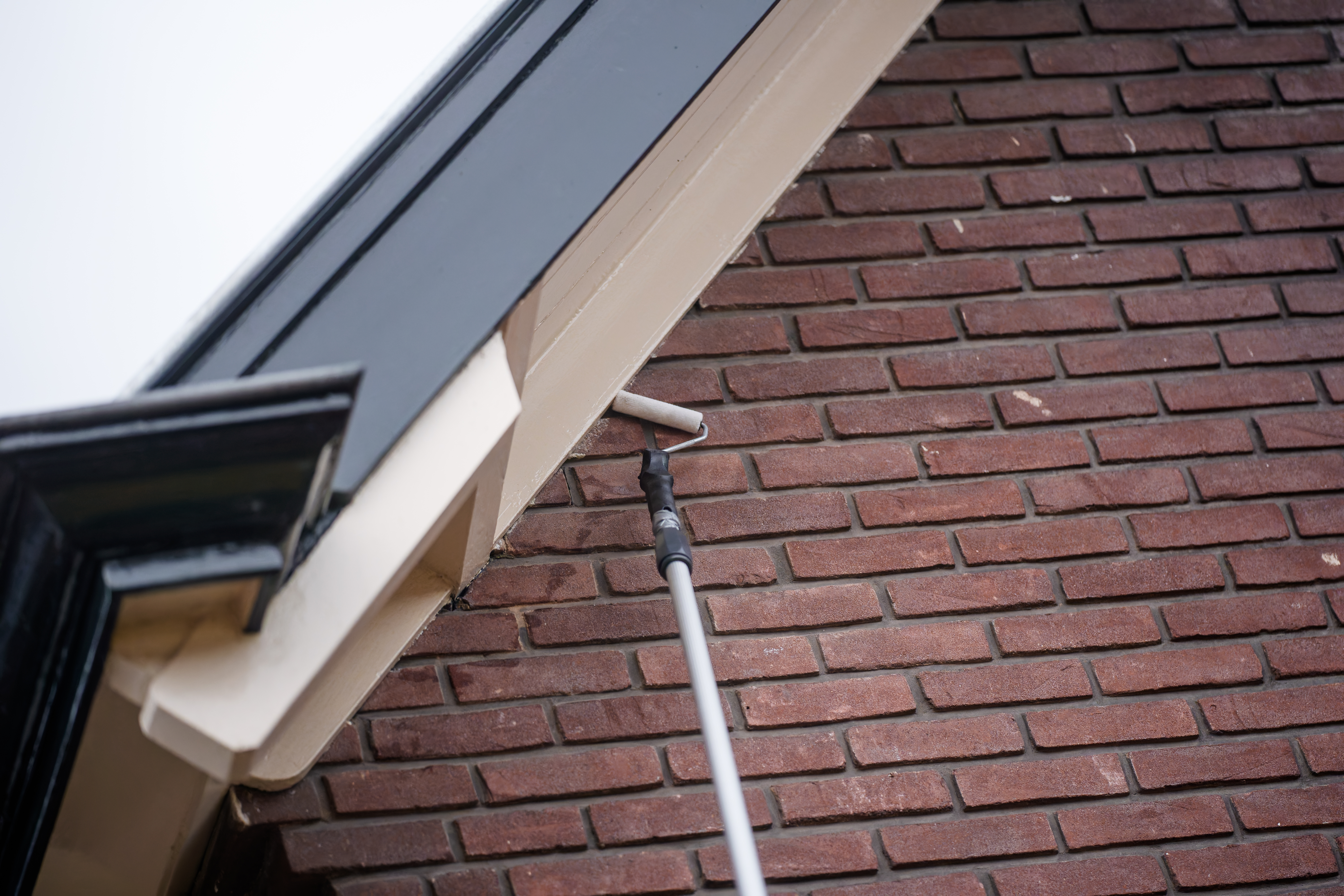 de roller gaat aan een lange stok langs de dakrand van het huis.