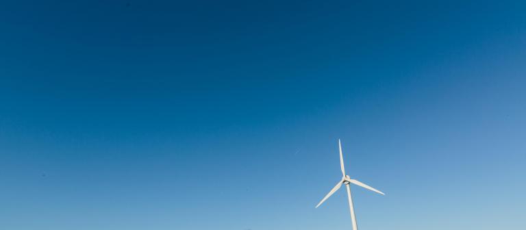 Foto van een windmolen tegen een blauwe lucht