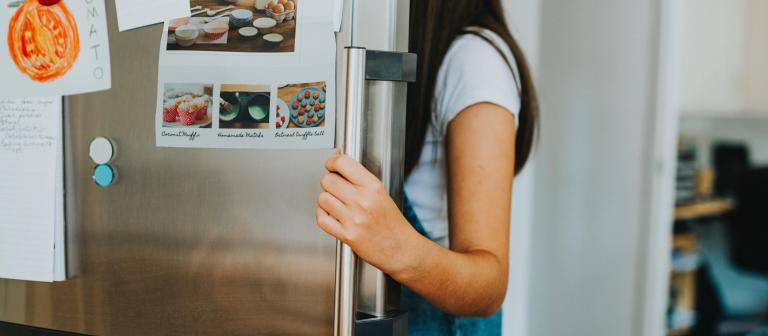 Foto van een vrouw die in de koelkast kijkt