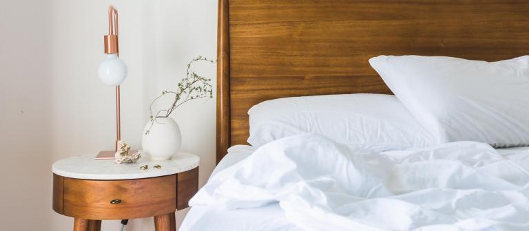 Foto van een houten bed met witte lakens