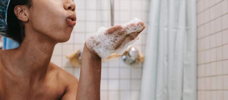 Foto van vrouw die doucheschuim van haar hand blaast