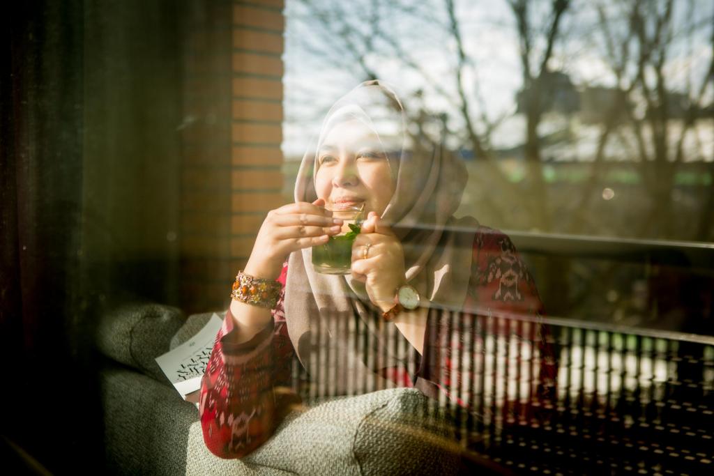 Foto van een vrouw die een kop thee drinkt achter een raam