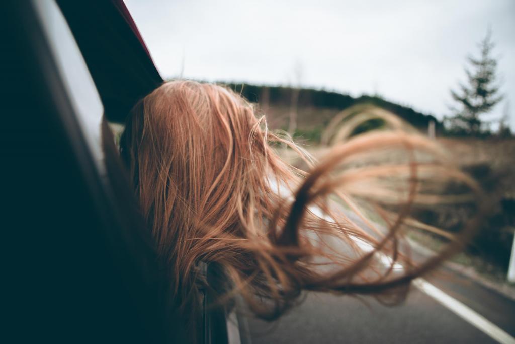 Foto van een vrouw die met haar haren uit de auto hangt