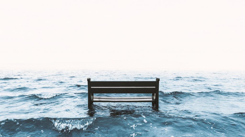 Foto van een bankje dat in zee verdwijnt