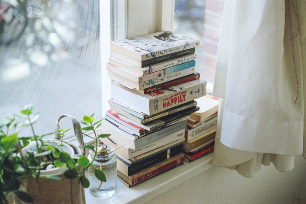 Foto van een stapel boeken voor een raam