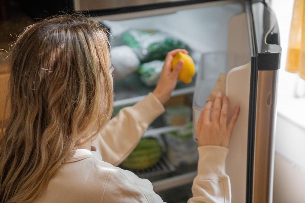 Foto van een vrouw die een citroen uit de koelkast pakt