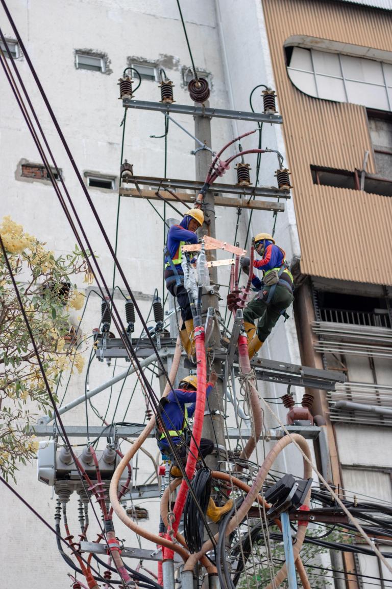 mannen werken aan kabels in elektriciteitsmast