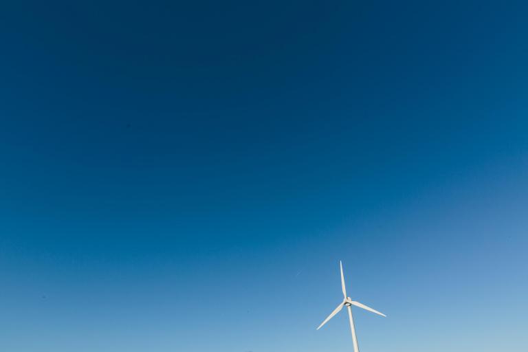 Foto van een windmolen tegen een blauwe lucht