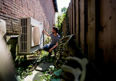 buitenunit van een luchtwaterwarmtepomp tegen een muur aan