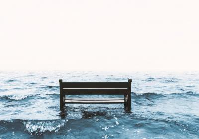 Foto van een bankje dat in zee verdwijnt