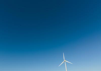 Foto van een windmolen tegen een blauwe lucht