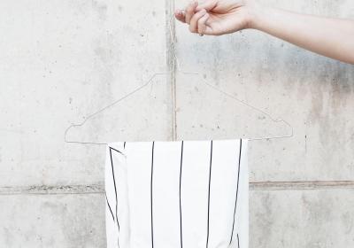 Foto van een witte broek op een kledinghanger voor een betonnen muur 