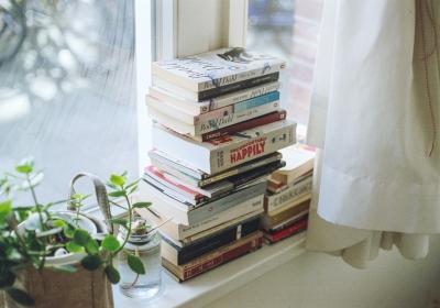 Foto van een stapel boeken voor een raam