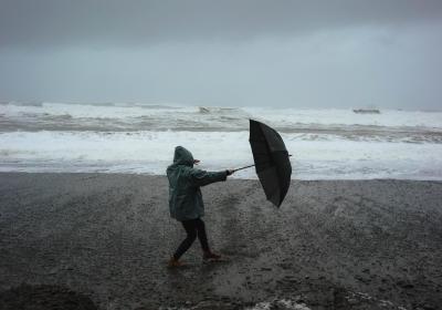 Foto van persoon met paraplu op het strand in een storm
