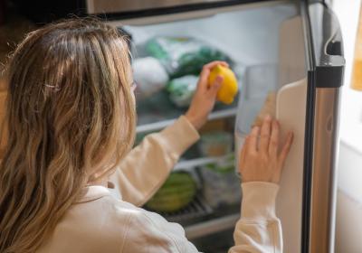 Foto van een vrouw die een citroen uit de koelkast pakt