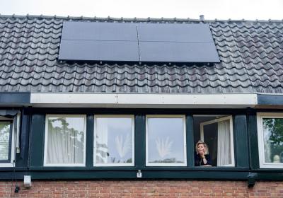 Vrouw in raamopening met zonnepanelen op dak 