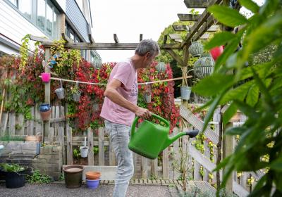 man met gieter in tuin